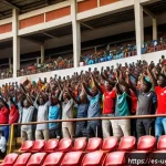 우간다 축구 리그 - A vibrant scene inside a renovated Ugandan football stadium filled with diverse families and groups ...